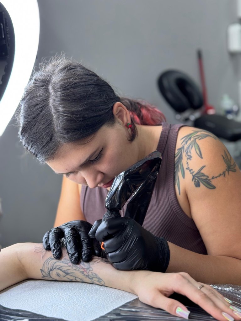 Alexandra S. tattooing a forearm in the studio
